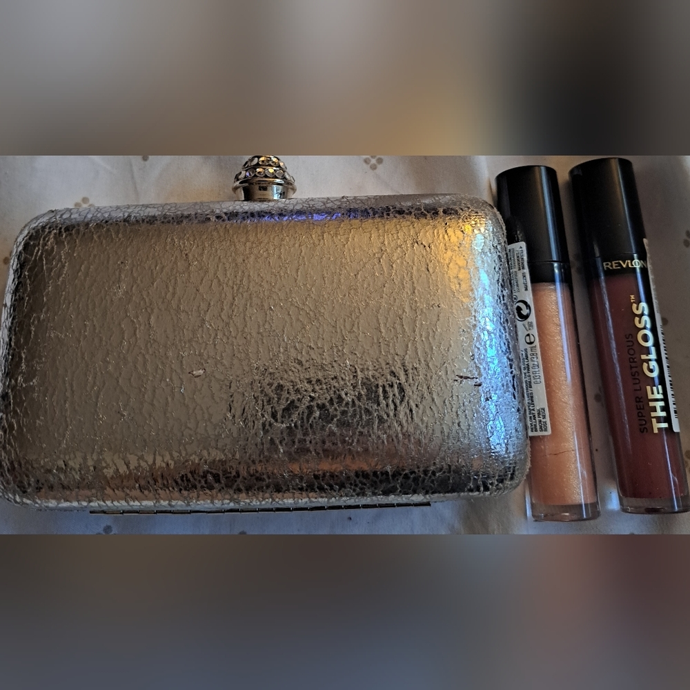 Bebe silver clutch. Revlon glosses are not included. Bag is brand new.